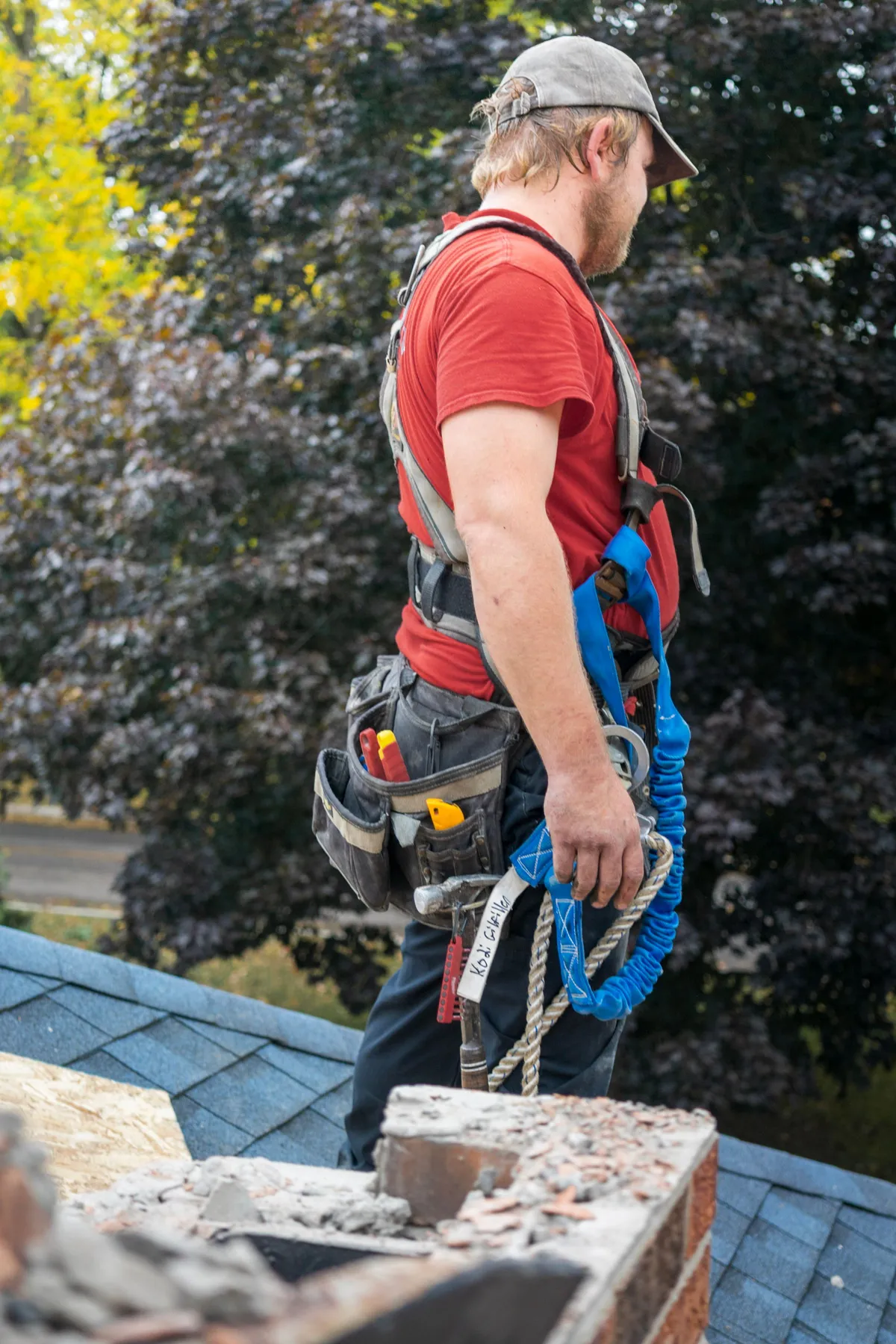 Roofer in a safety harness working near a chimney